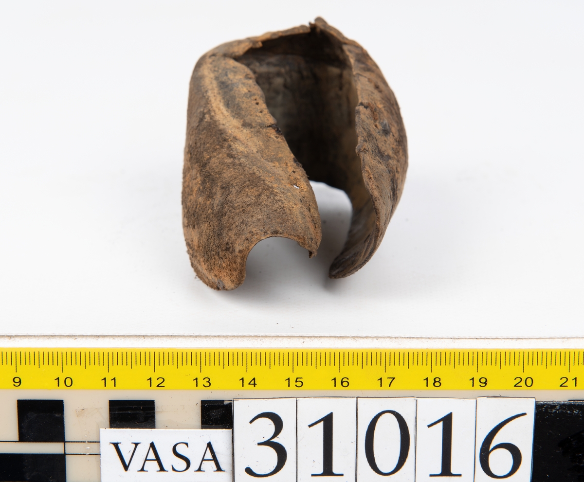 Ovanläder och bakkappa till sko. Längs med ovanlädrets ytterkant löper en enkel rad med stygnshål. Narvytan är välbevarad och har en rutmönstrad struktur. Bakkappans nedre kant är vikt. Kanten har legat invikt och suttit fästad i sulpaketet.