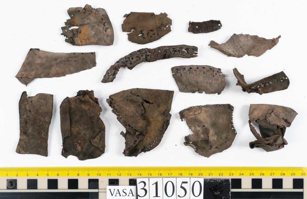 Dokumentation 1997:
Delar och fragment från sko.
Fyra sulor, fyndnummer 31050, 31050:1, 310502 samt 31050:4. Runt sulornas ytterkanter löper hål efter stygns och träpligg. Två av sulorna, fyndnummer 31050 och 31050:1, är spaltade. Lädret är mycket sprött. Sulor fyndnummer 31050:2 och 31050:3 består av ett relativt kraftigt läder. Sula fyndnummer 31050:3 är avskuren vid tåpartiet. Eventuellt kandenna sula härröra från en annan skobotten.
En bakkappa, fyndnummer 31050:4. Längs med ytterkanterna löper stygnshål. lädret är spaltat och sprött.
Ett 40-tal delar och fragment av sulor, inlägg, ovanläder mm.

Även växtfibrer.

Dokumentation 2022:
Bindsula till en svensksko. Tillverkad i läder. Inga dekorationer. Hör ihop med fyndnummer 11317. Framdelen saknas. Sättet bäraren använde skon tyder på att hen hade metatarsalgi. Det finns inga tecken på lagningar. 
För mer information, se Länkade filer: Uppritning

Text in english:
This is the insole of a shoe, made of leather, of stitch-down construction, made on a right last and worn on the right foot, with no decorative features, it pairs with 11317. The pieced front of the insole is missing and the way the weight of the wearer imprinted on the insole suggests that they had a depressed transverse metatarsal arch. There are no signs of repairs.
For more information, go to Länkade filer: Uppritning