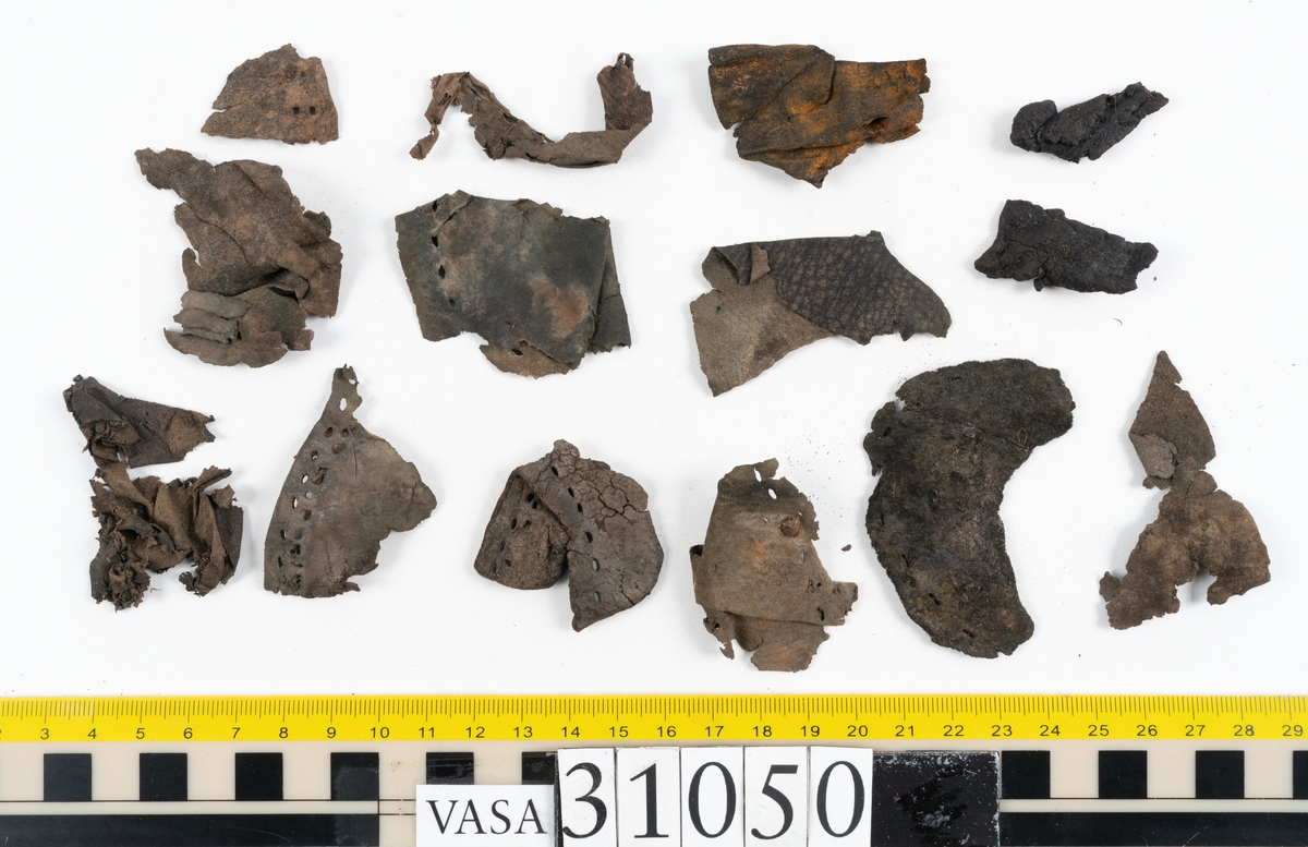 Dokumentation 1997:
Delar och fragment från sko.
Fyra sulor, fyndnummer 31050, 31050:1, 310502 samt 31050:4. Runt sulornas ytterkanter löper hål efter stygns och träpligg. Två av sulorna, fyndnummer 31050 och 31050:1, är spaltade. Lädret är mycket sprött. Sulor fyndnummer 31050:2 och 31050:3 består av ett relativt kraftigt läder. Sula fyndnummer 31050:3 är avskuren vid tåpartiet. Eventuellt kandenna sula härröra från en annan skobotten.
En bakkappa, fyndnummer 31050:4. Längs med ytterkanterna löper stygnshål. lädret är spaltat och sprött.
Ett 40-tal delar och fragment av sulor, inlägg, ovanläder mm.

Även växtfibrer.

Dokumentation 2022:
Bindsula till en svensksko. Tillverkad i läder. Inga dekorationer. Hör ihop med fyndnummer 11317. Framdelen saknas. Sättet bäraren använde skon tyder på att hen hade metatarsalgi. Det finns inga tecken på lagningar. 
För mer information, se Länkade filer: Uppritning

Text in english:
This is the insole of a shoe, made of leather, of stitch-down construction, made on a right last and worn on the right foot, with no decorative features, it pairs with 11317. The pieced front of the insole is missing and the way the weight of the wearer imprinted on the insole suggests that they had a depressed transverse metatarsal arch. There are no signs of repairs.
For more information, go to Länkade filer: Uppritning