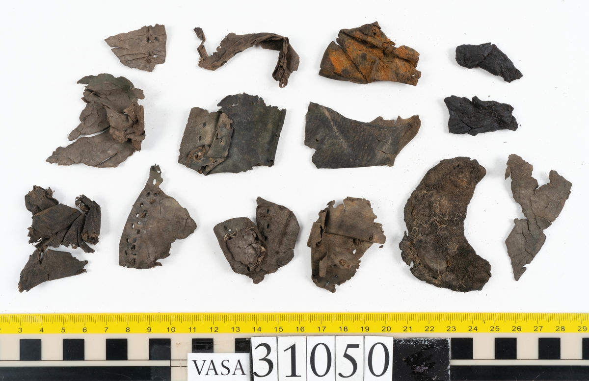 Dokumentation 1997:
Delar och fragment från sko.
Fyra sulor, fyndnummer 31050, 31050:1, 310502 samt 31050:4. Runt sulornas ytterkanter löper hål efter stygns och träpligg. Två av sulorna, fyndnummer 31050 och 31050:1, är spaltade. Lädret är mycket sprött. Sulor fyndnummer 31050:2 och 31050:3 består av ett relativt kraftigt läder. Sula fyndnummer 31050:3 är avskuren vid tåpartiet. Eventuellt kandenna sula härröra från en annan skobotten.
En bakkappa, fyndnummer 31050:4. Längs med ytterkanterna löper stygnshål. lädret är spaltat och sprött.
Ett 40-tal delar och fragment av sulor, inlägg, ovanläder mm.

Även växtfibrer.

Dokumentation 2022:
Bindsula till en svensksko. Tillverkad i läder. Inga dekorationer. Hör ihop med fyndnummer 11317. Framdelen saknas. Sättet bäraren använde skon tyder på att hen hade metatarsalgi. Det finns inga tecken på lagningar. 
För mer information, se Länkade filer: Uppritning

Text in english:
This is the insole of a shoe, made of leather, of stitch-down construction, made on a right last and worn on the right foot, with no decorative features, it pairs with 11317. The pieced front of the insole is missing and the way the weight of the wearer imprinted on the insole suggests that they had a depressed transverse metatarsal arch. There are no signs of repairs.
For more information, go to Länkade filer: Uppritning