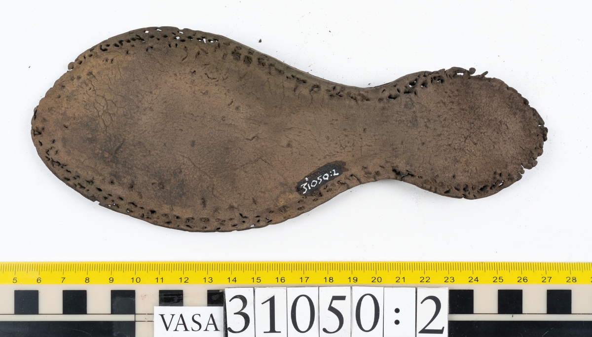 Dokumentation 1997:
Delar och fragment från sko.
Fyra sulor, fyndnummer 31050, 31050:1, 310502 samt 31050:4. Runt sulornas ytterkanter löper hål efter stygns och träpligg. Två av sulorna, fyndnummer 31050 och 31050:1, är spaltade. Lädret är mycket sprött. Sulor fyndnummer 31050:2 och 31050:3 består av ett relativt kraftigt läder. Sula fyndnummer 31050:3 är avskuren vid tåpartiet. Eventuellt kandenna sula härröra från en annan skobotten.
En bakkappa, fyndnummer 31050:4. Längs med ytterkanterna löper stygnshål. lädret är spaltat och sprött.
Ett 40-tal delar och fragment av sulor, inlägg, ovanläder mm.

Även växtfibrer.

Dokumentation 2022:
Bindsula till en svensksko. Tillverkad i läder. Inga dekorationer. Hör ihop med fyndnummer 11317. Framdelen saknas. Sättet bäraren använde skon tyder på att hen hade metatarsalgi. Det finns inga tecken på lagningar. 
För mer information, se Länkade filer: Uppritning

Text in english:
This is the insole of a shoe, made of leather, of stitch-down construction, made on a right last and worn on the right foot, with no decorative features, it pairs with 11317. The pieced front of the insole is missing and the way the weight of the wearer imprinted on the insole suggests that they had a depressed transverse metatarsal arch. There are no signs of repairs.
For more information, go to Länkade filer: Uppritning