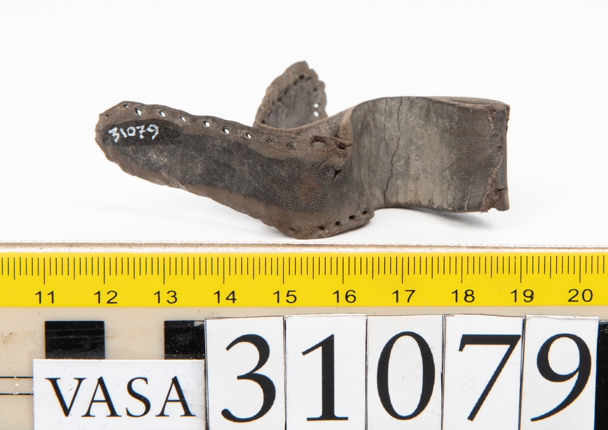 Två delar tillhörande en stövel: en stropp samt en del av en stropp från ett stövelskaft.

Den ena stroppen ligger dubbelvikt. I två av ändarna finns stygnshål efter fastsättningen. Lädret är välbevarat.

Den andra stroppen är fragmentarisk. I ena änden finns stygnshål i forman av en rektangel. Lädret är sprucket och något spaltat.