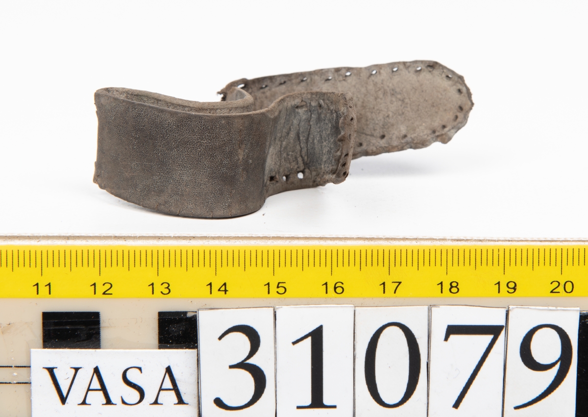 Två delar tillhörande en stövel: en stropp samt en del av en stropp från ett stövelskaft.

Den ena stroppen ligger dubbelvikt. I två av ändarna finns stygnshål efter fastsättningen. Lädret är välbevarat.

Den andra stroppen är fragmentarisk. I ena änden finns stygnshål i forman av en rektangel. Lädret är sprucket och något spaltat.