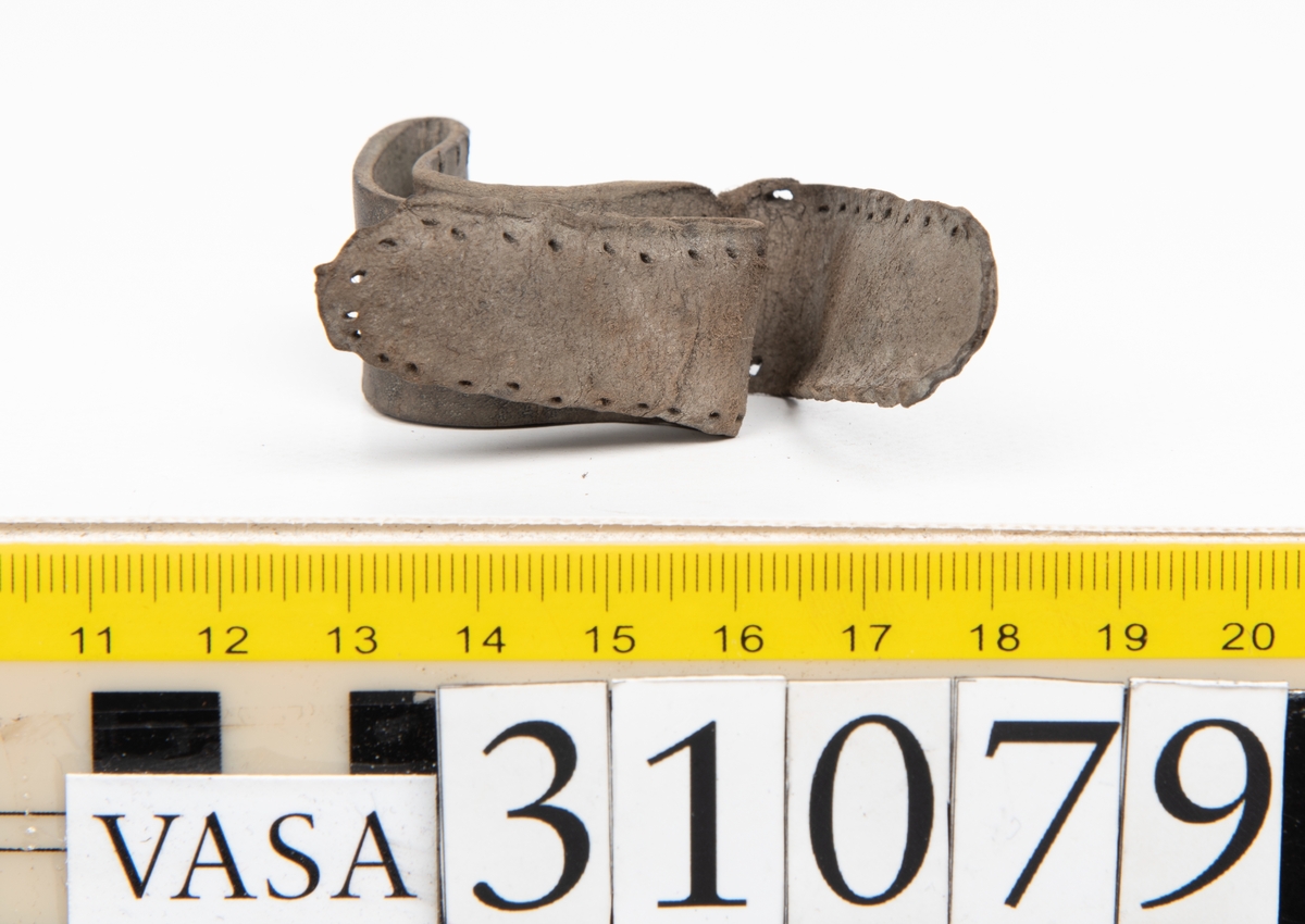 Två delar tillhörande en stövel: en stropp samt en del av en stropp från ett stövelskaft.

Den ena stroppen ligger dubbelvikt. I två av ändarna finns stygnshål efter fastsättningen. Lädret är välbevarat.

Den andra stroppen är fragmentarisk. I ena änden finns stygnshål i forman av en rektangel. Lädret är sprucket och något spaltat.