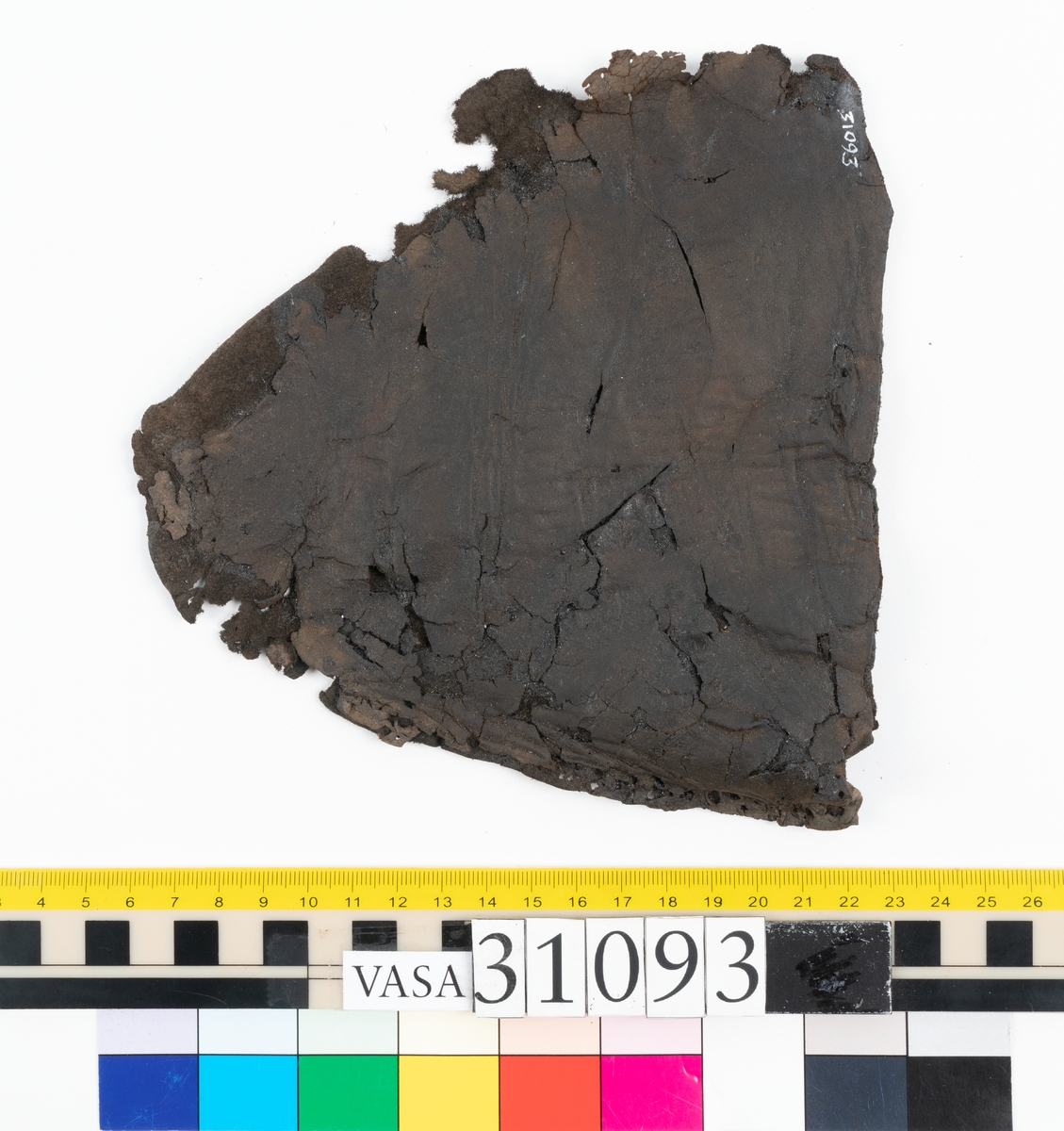 Ett ovanläder till en sko. Ovanlädrets övre kant är rakt avskuren och saknar tunga. Nedanför den övre kanten sitter två snörhål. Längs med ytterkanterna löper stygnshål. Ena ytterkanten är fragmentarisk.