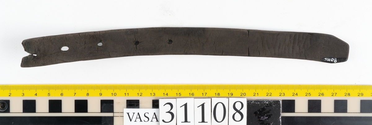 Två delar av en läderrem.
Den längsta delen av remmen är försedd med fem hål. Det femte hålet är placerat vid remmens fragmentariska ände. Den motsvarande änden är kantigt skuren. Lädret är mycket kraftigt och välbevarat.
Den kortare delen av remmen är försedd med en fragmentarisk ände samt en rakt skuren eller avklippt ände. Strax innanför den skurna änden finns ett större hål som är försett med fasade kanter. Narvsidan är så gott som helt bortspaltad, i övrigt är lädret kraftigt och relativt välbevarat.