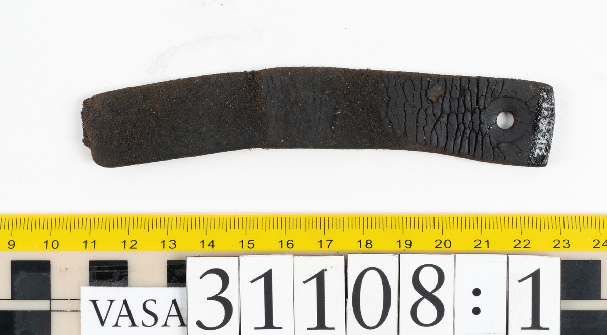 Två delar av en läderrem.
Den längsta delen av remmen är försedd med fem hål. Det femte hålet är placerat vid remmens fragmentariska ände. Den motsvarande änden är kantigt skuren. Lädret är mycket kraftigt och välbevarat.
Den kortare delen av remmen är försedd med en fragmentarisk ände samt en rakt skuren eller avklippt ände. Strax innanför den skurna änden finns ett större hål som är försett med fasade kanter. Narvsidan är så gott som helt bortspaltad, i övrigt är lädret kraftigt och relativt välbevarat.