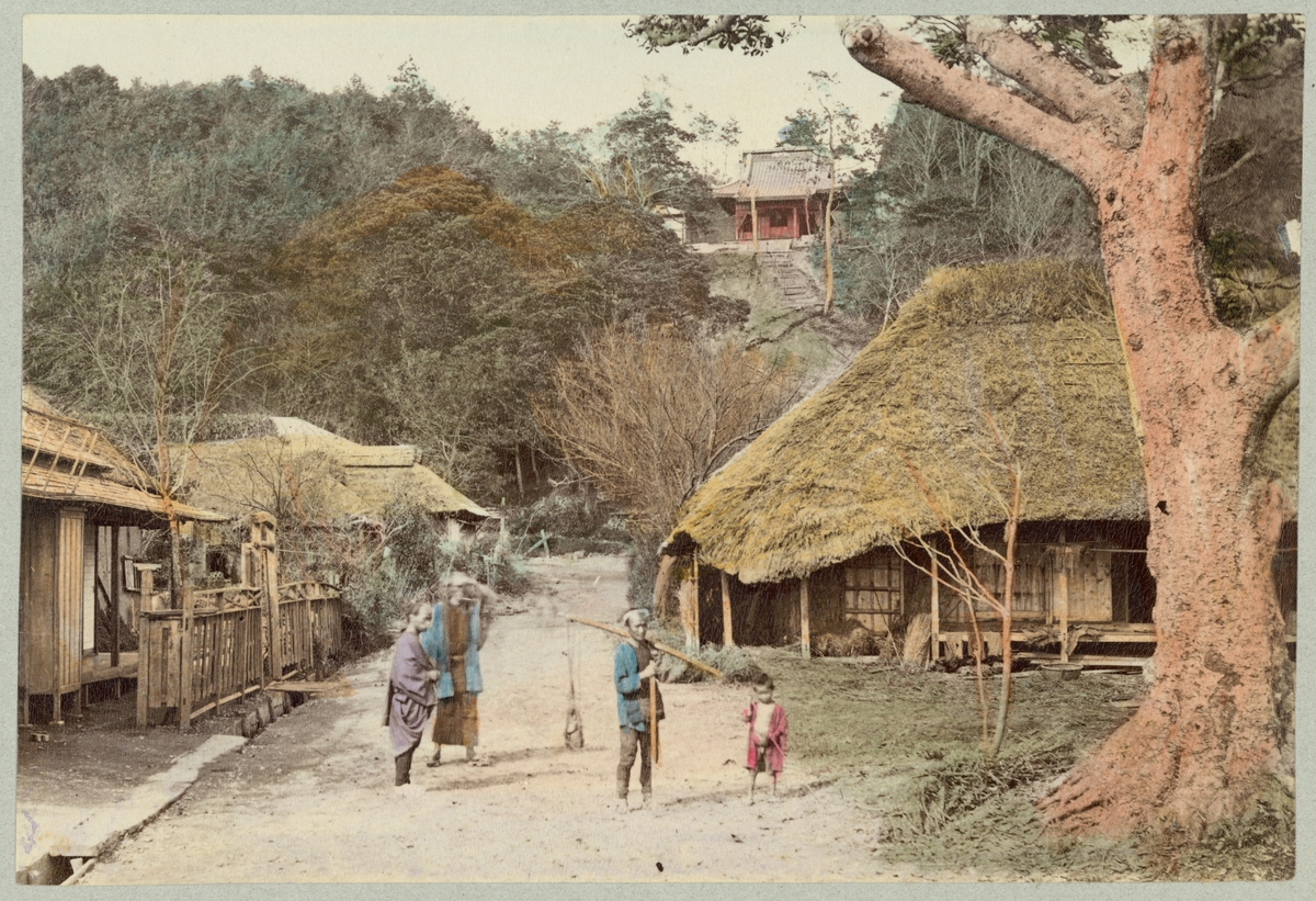 Bilden visa en gata i en by vid staden Nikko i Japan. Mitt på gatan står en grupp människor i traditionella kläder som vänder sig mot fotografen. By består av enkla trähus med halmtak. På berget ovanpå byn syns en röd träbyggnad med tegeltak som verka tillhöra en av shintohelgedomar i Nikko.