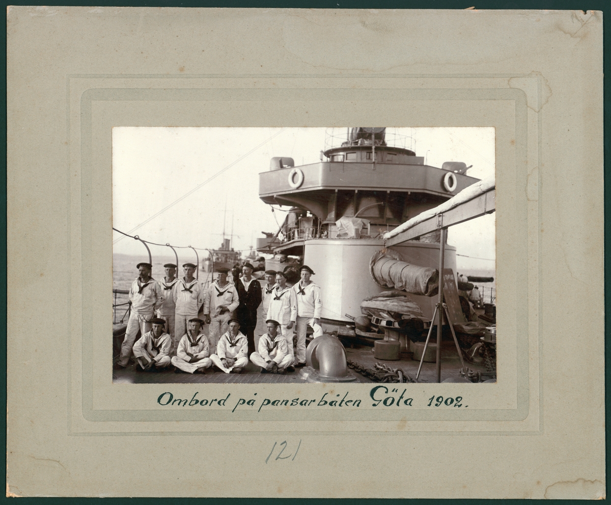 Denna grupporträtt föreställer manskap kläd i vita sjömanskostymer ombord på pansarbåten Göta 1902.
