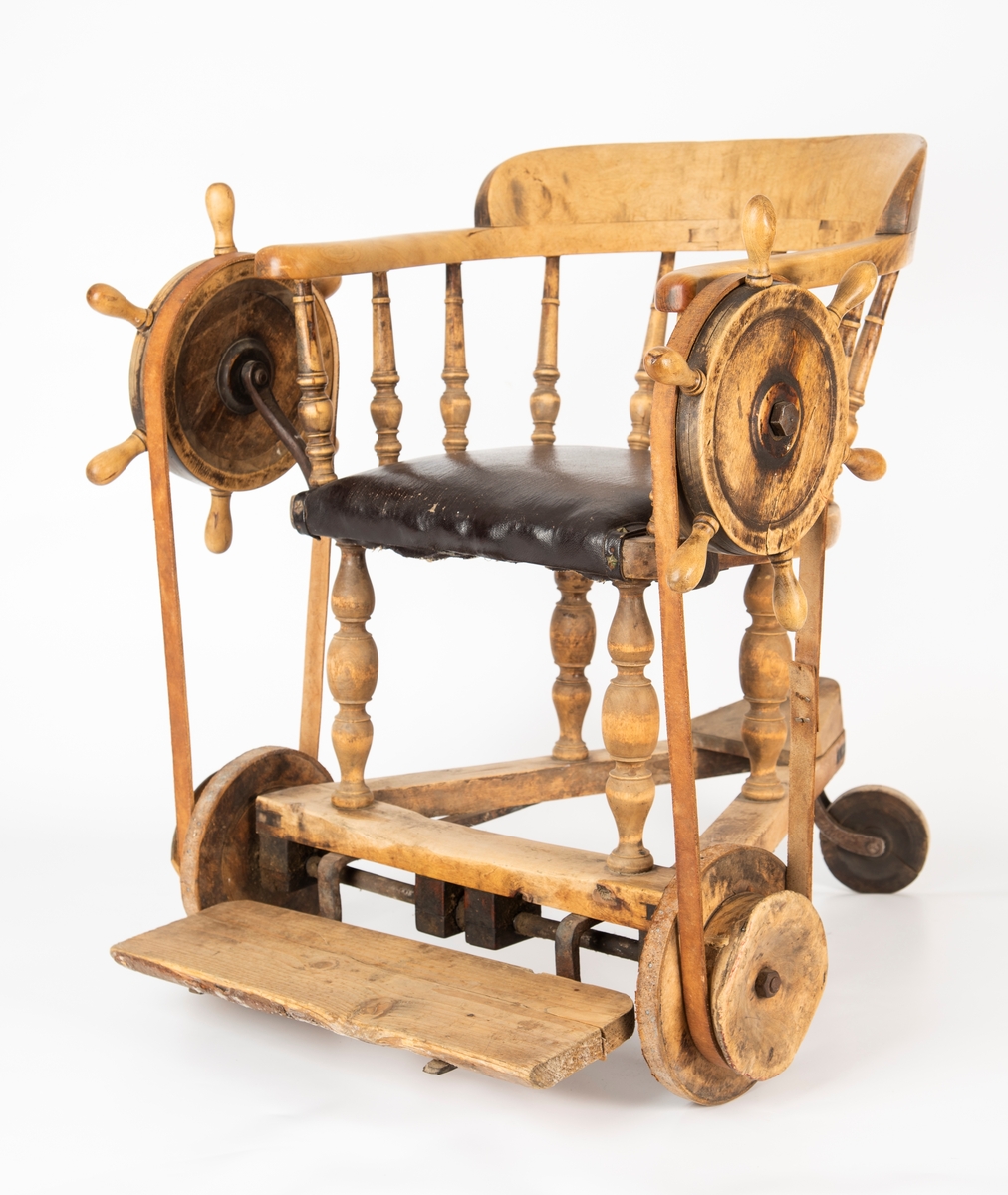 Rullestol i tre, med sete i skinn.