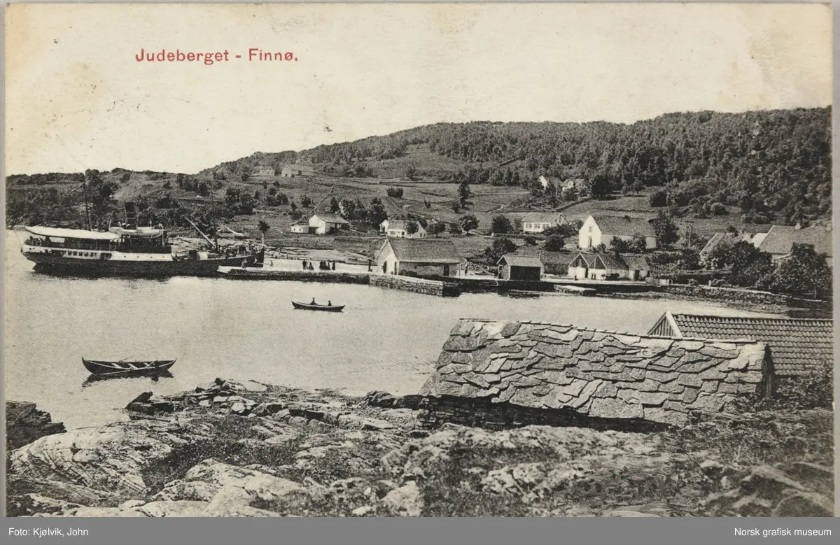 Postkort med bilde av havna i Judaberg. Det er ei stor brygge og flere sjøhus. Et passasjerskip ligger til kai.