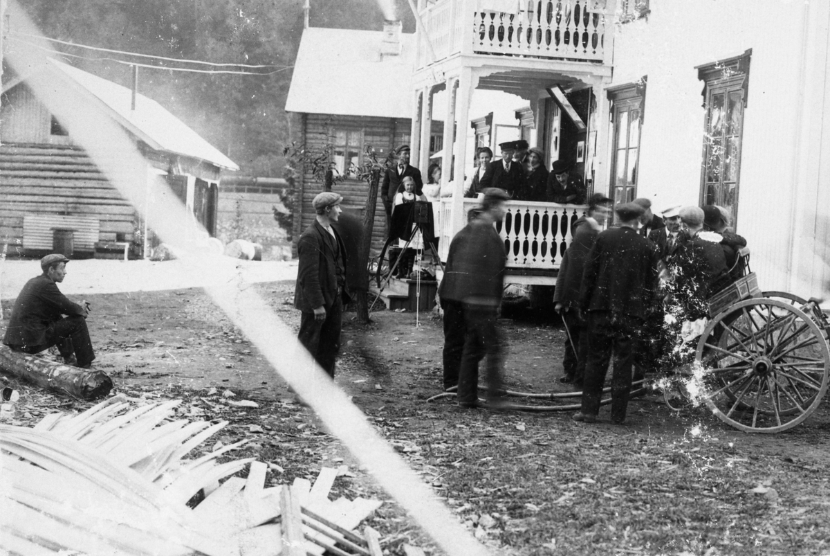 Fotosamling etter Øystein O. Kaasa. (1877-1923). Motiv folk og reisende fotografert ved tralle. Fra fotografering. Fotoapparat er plassert mot arrangeringen av gruppen. Utydelig påskrift, ant. Vestfjorddalen. Antatt avfotografering.