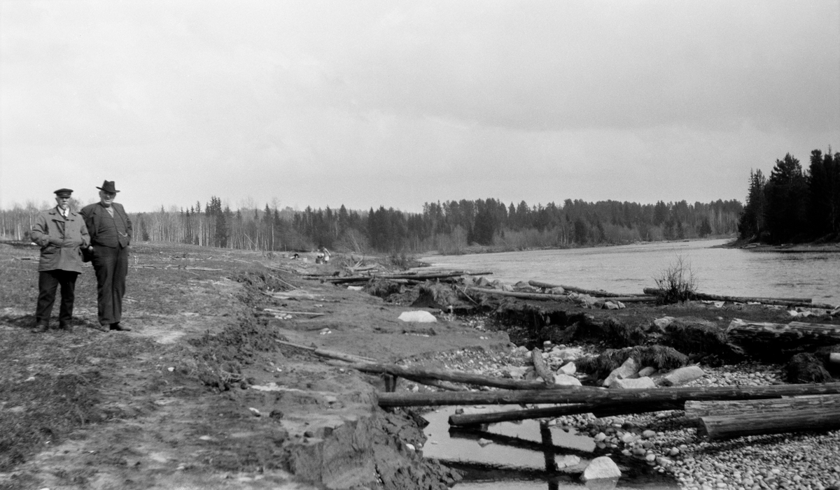 Parti fra Kilen ved Flisavassdraget, et sidevassdrag til Glomma i Åsnes kommune i Hedmark.  Fotografiet er tatt fra nordsida av elveløpet, som flyter bredt og stille til høyre i bildet.  Langs land i forgrunnen ligger en del barkete tømmerstokker igjen etter fløtinga.  Landskapet bærer ellers preg av at elva har gravd med seg en del masse fra strendene i forgrunnen.  To menn til venstre i bildet står og betrakter forholdene. 

Det var særlig eiendommen til Bernt Jonsen Kilen (1854-1931) som var rammet av dette erosjonsproblemet i denne delen av Flisavassdraget. 

Fotografiene SJF.1989-02283, SJF.1989.02720 og SJF.1989-02721 er tatt i samme område for å dokumentere elvas eroderende virkninger.