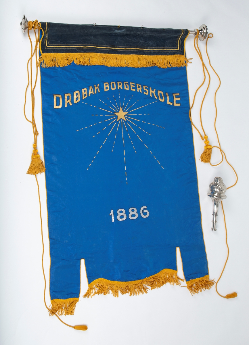 Skolefane for Drøbak borgerskole/Drøbak høiere almenskole. Fanen laget til skolen 50-års jubileum i 1936. Silke eller kunstsilke. 
Ene siden rødt stoff med malt skrift og dekorasjon i sølv og gull: 
"DRØBAK HØIERE ALMENSKOLE   Å TENKE FRITT ER STORT   Å TENKE RETT ER STØRRE"
"1886 23 august. 1936 23. august"

Den andre siden blått stoff med malt dekorasjon i gull: Stjerne med stråler "DRØBAK BORGERSKOLE" 
En mørk blå fløyelskant dekker fanen helt øverst. Denne kan være sekundær. 
Fanen er utstyrt med gullsnorer og dusker. Fanen er festet til en trestang med store metallkuler i endene. Trestangen kan være sekundær da det ser ut til at metallkulene har vært festet annerledes. 
Mye tyder på at fanen har vært hengt opp da det er kroker festet til stangen.

Påskrift: Drøbak Borgerskole 1886.
             Drøbak høiere allmennskole
             Å tenke fritt er stort
             Å tenke rett er større