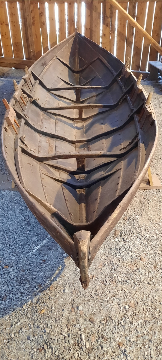 Båt. Nordfjordbåt. Seksæring. For årer og segl (råsegl). Klinkbygd trebåt med 4 omfar. Tjæra innvendig og utvendig, mørk brun farge. På oversida av ripbordet er det ei slitelist som er spikra ned ovanfrå. Firkanta roer.