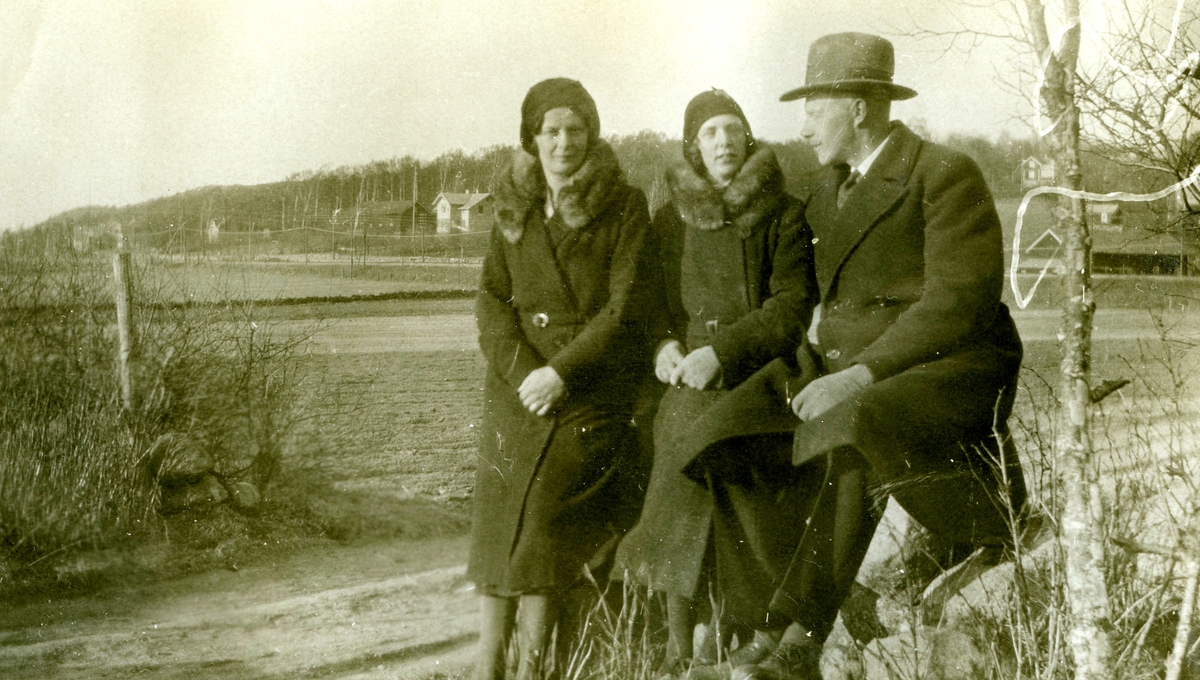 Systrarna Astrid (1907 - 1994, gift Jägerström) och Ingeborg Gustafsson (1901 - 1987, gift Johansson) från Kållered stom "Nygård" samt en okänd man står vid en landsväg i Kållered (där Eken center ligger idag), 1930-tal. I bakgrunden till vänster skymtar gården Kållered Stom "Nygård" som revs år 1970. Den låg utefter järnvägen och Gamla Riksvägen.