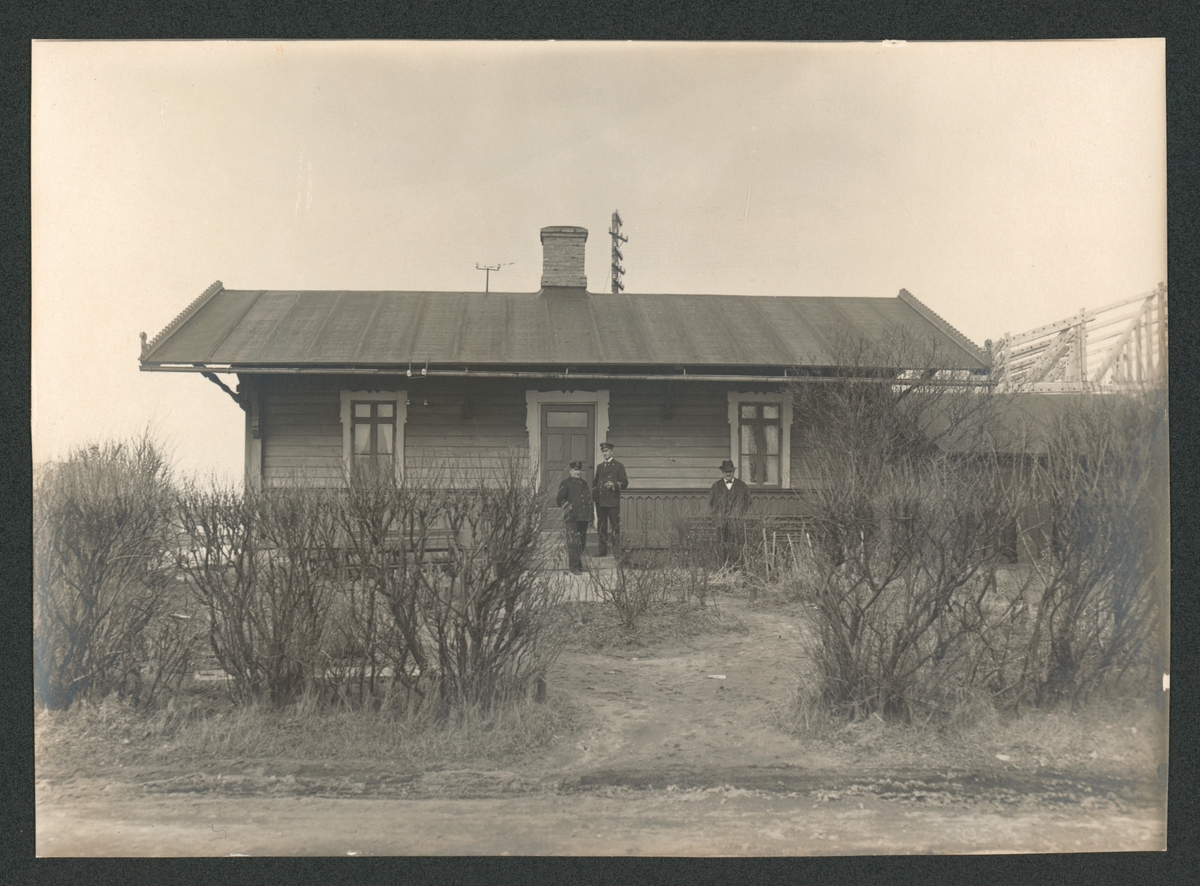 På bilden syns Lotsstugan på Stumholmen. Personerna på bilden är sannolikt fyrmästare Karlberg och lotsar-
na John Löfgren f.1871 och John Lång, förmodligen överlots. I bakgrunden till höger syns flyghangaren under
uppförande, alltså ca 1915.