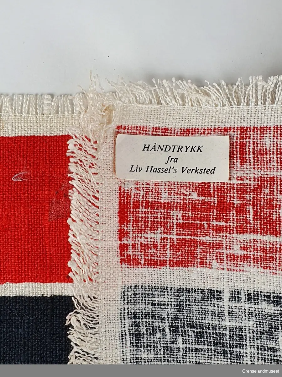 Håndtrykket brikke eller veggbilde. Rød, sort, hvit. Rektangulær. Breddeformat. Motiv: tre vikinger.

Merkelapp: Liv Hassels verksted.