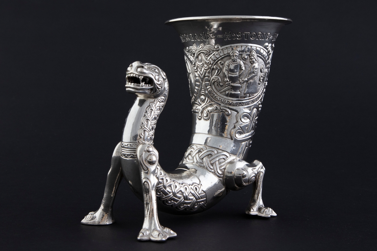 På øvre del av drikkehornet er det tre sirkulære felter med motiver fra historien om Sigurd Favnesbane, hentet fra Hyllestadportalen. De er omgitt av ranker og flettverkornamentikk. De tre scenene er flankert av innskrifter. Figurene er sterkt stiliserte.

1) "REGIN smeder SVERDET". Scenen viser Regin og Sigurd som smir sverdet på en ambolt, med flammende ild i bakgrunnen. 

2) "SIGURD pröver SVERDET". Scenen viser Sigurd som slår sverdet mot armbolten, og det brekker i to. Regin står sentralt i feltet og betrakter hendelsen.

3) "SIGURD dreper DRAGEN". Scenen viser Sigurd som dreper den buktende dragen Favne. Den er bygget opp gjennom en horror vacui-prinsipp, hvor figurene fyller hele billedfeltet.