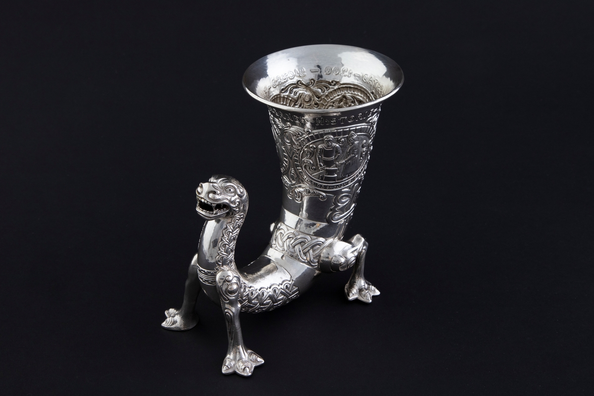 På øvre del av drikkehornet er det tre sirkulære felter med motiver fra historien om Sigurd Favnesbane, hentet fra Hyllestadportalen. De er omgitt av ranker og flettverkornamentikk. De tre scenene er flankert av innskrifter. Figurene er sterkt stiliserte.

1) "REGIN smeder SVERDET". Scenen viser Regin og Sigurd som smir sverdet på en ambolt, med flammende ild i bakgrunnen. 

2) "SIGURD pröver SVERDET". Scenen viser Sigurd som slår sverdet mot armbolten, og det brekker i to. Regin står sentralt i feltet og betrakter hendelsen.

3) "SIGURD dreper DRAGEN". Scenen viser Sigurd som dreper den buktende dragen Favne. Den er bygget opp gjennom en horror vacui-prinsipp, hvor figurene fyller hele billedfeltet.