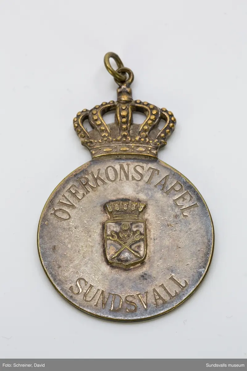 Rund bricka med upphöjd mitt med stadsvapnet.