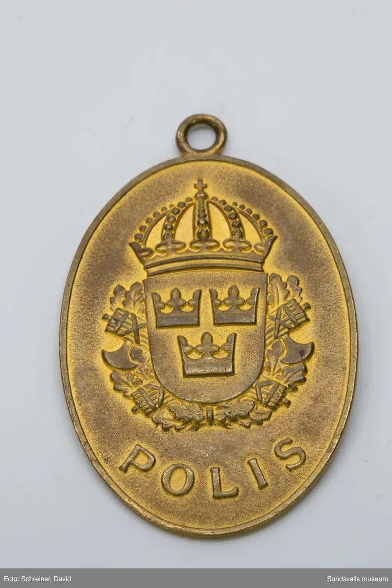 På framsidan med riksvapnet i skölden och bakom eklövskrans runt skölden
