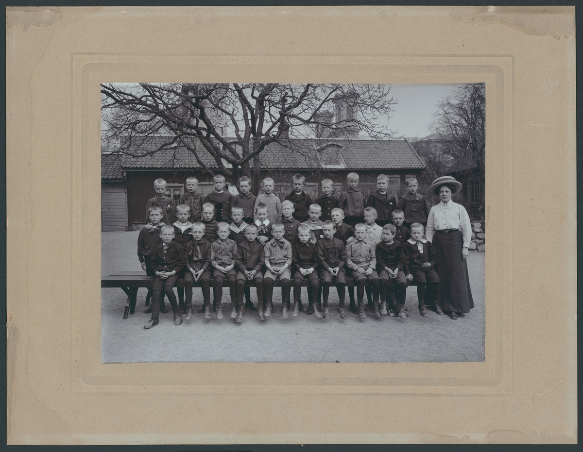 Bilden föreställer en gruppfoto av en skolklass från Amiralitetsskolan i Kungsgatan. En av pojkarna är f.d. Dir. Nils Löwenberg, Karlskrona, 2:a raden längst ut till höger. Kvinnan på bilden kan vara fröken Karlberg.