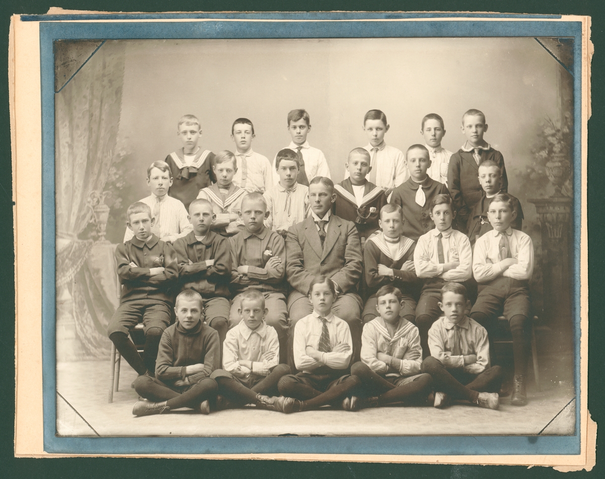 Bilden föreställer en gruppfoto av en skolklass från Amiralitetsskolan i Kungsgatan med läraren i mitten. En av pojkarna är f.d. Dir. Nils Löwenberg, Karlskrona, 2:a raden längst ut till höger.