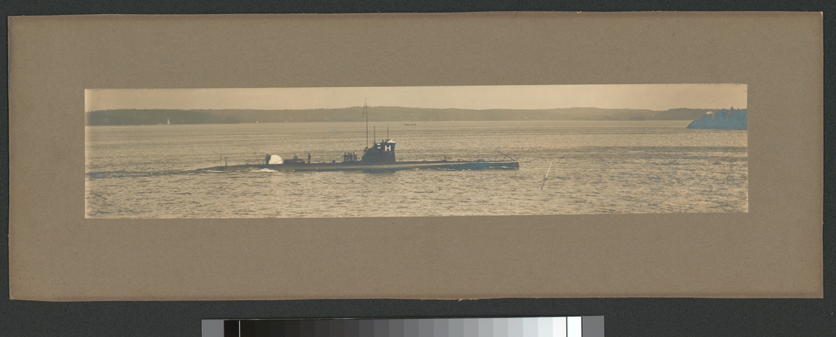 Bilden föreställer ubåten Hajen till sjöss. Båten gör låg fart. På däck står en grupp besättningsmän i samtal medan andra håller på med olika arbeten.