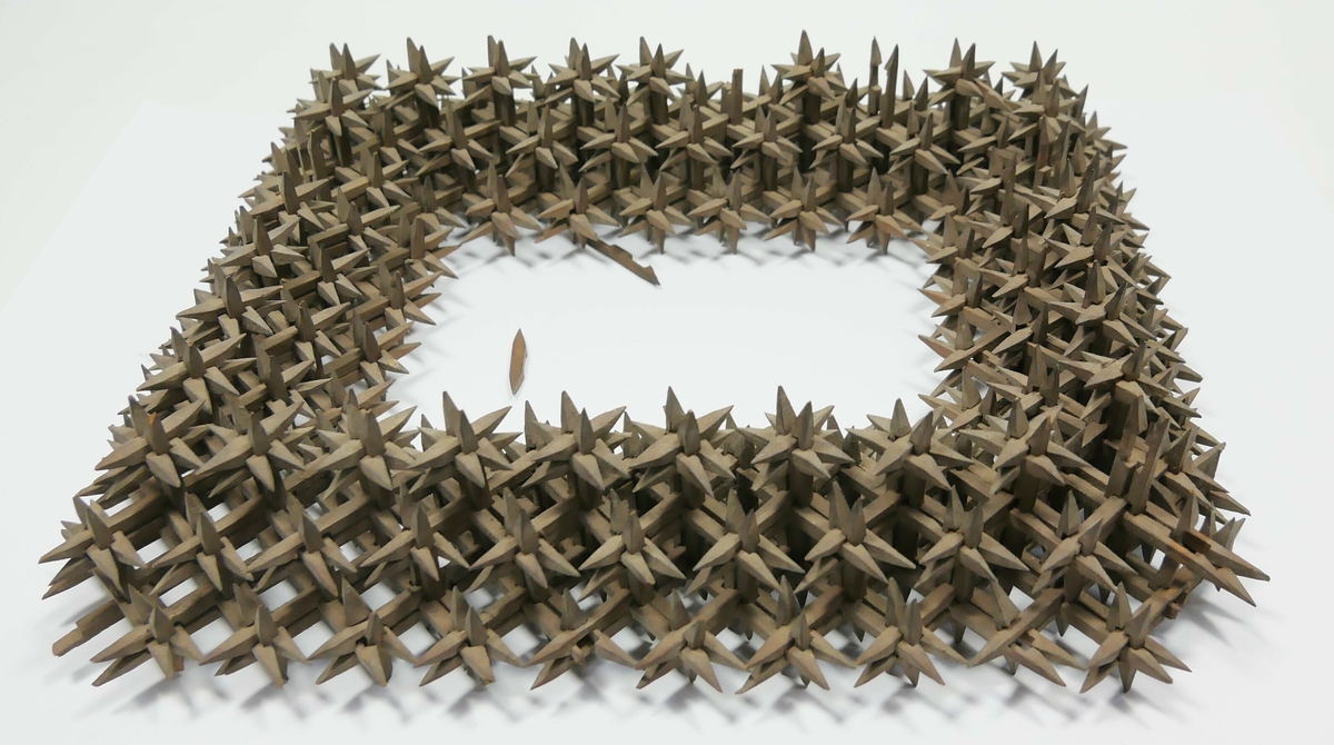 Rektangulær bilderamme laga av skråtobakkspinner som er satt saman. 