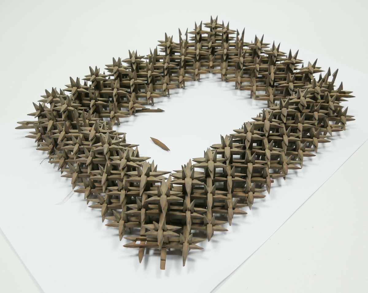 Rektangulær bilderamme laga av skråtobakkspinner som er satt saman. 