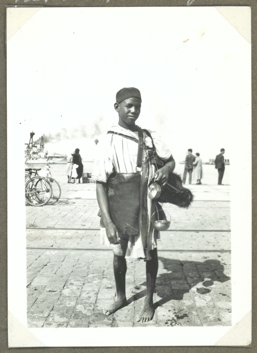 På bilden syns en pojke som säljer vatten i ett hamnområde i Marocko.