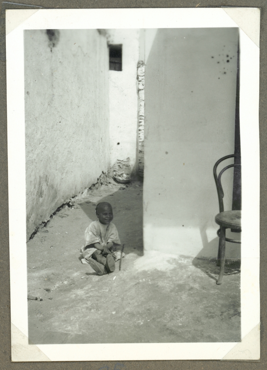 Bilden visar en arabisk barn som sitter på en gata. På höger bildkanten syns en stol från Thonet nr 14 som har hittat sin väg i en marockansk medina.