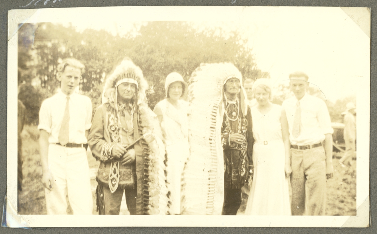 En gruppfoto med två indianhövdingar i traditionella dräkter och fyra besökare i västerländska kläder.