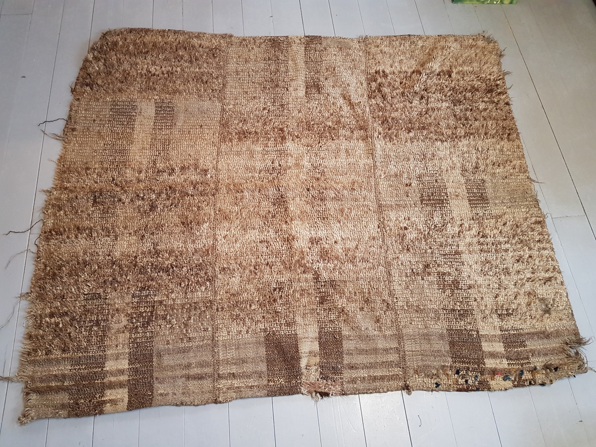En vevd tekstil bestående av 3 lengder sydd sammen, hver lengde er på 60 cm, det er innslag av floss på tekstilen, det er ull i renning og ull i innslag vevd i diagonalkypert