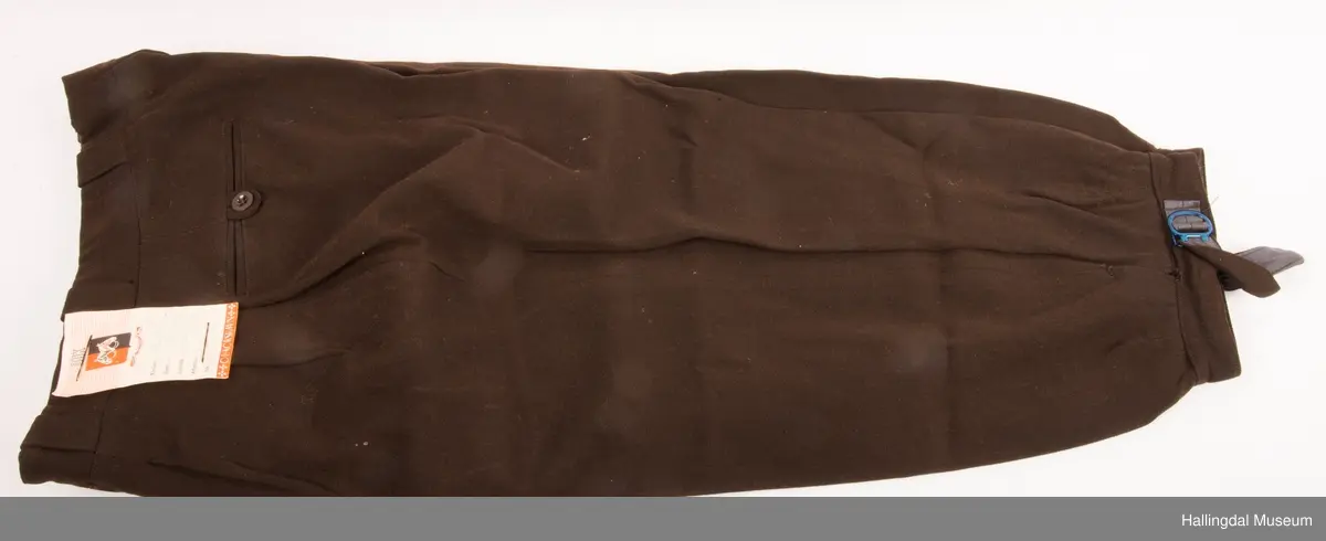 Mørk brun eplenikkers med 2 lommer framme i sidene og to lommer bak.  Spensel under kneet. Ubrukt bukse med merkelapp.