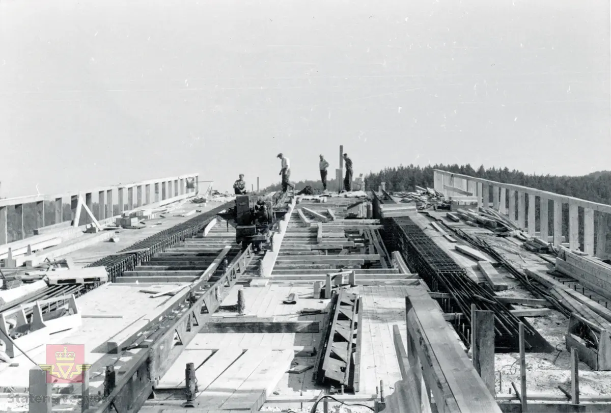 Fra bygging av Tromøybrua som ble åpnet 21. oktober 1961.  
Betongen blir transportert ut på brua. Bilde av armerte betongdragere som er klare for støping. 
Til venstre i bildeti ser også snekkernes private redskapskasser som står på brua.

Vegbru. Hengebru med fagverk, ingen opphengte sidespenn. Lengde 400, 30 meter. 
Kilde: Statens vegvesen sitt bruregister  " Brutus" nr. 09-0406.

Stedsnavn: Tromøy