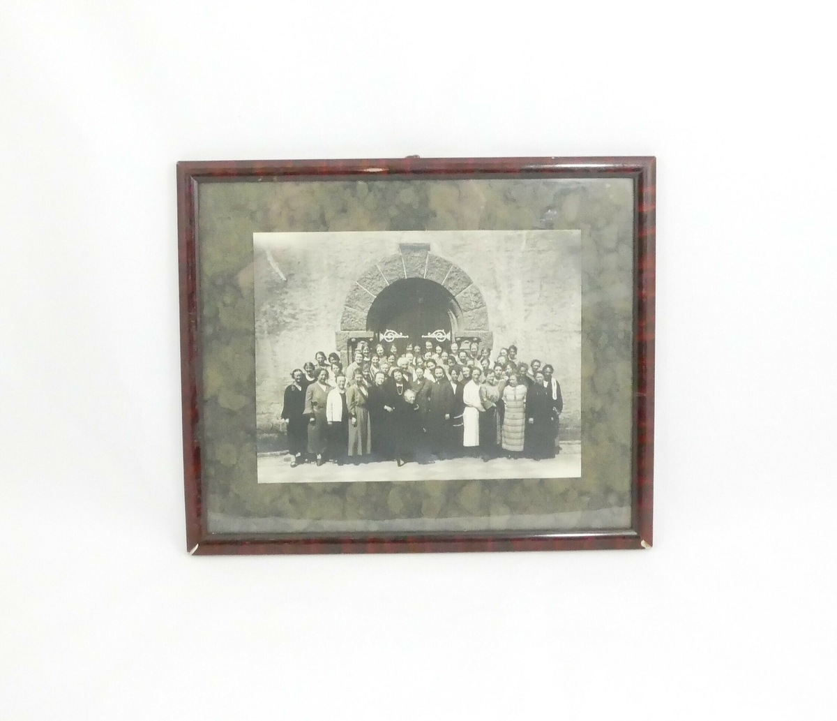 En større gruppe med kvinner i ulike alder står foran en dobbel tredør med jernbeslag og en portal med steinutsmykning. Det er usikkert hvem kvinnene er og hvor bildet er tatt. 