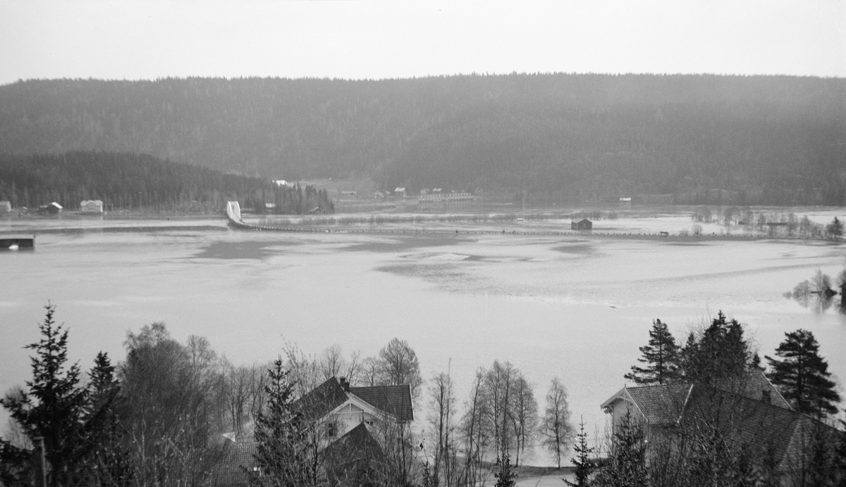 Flom i Glomma ved Rena i Åmot i Hedmark 6. mai 1934. Fotografiet er tatt fra lia på østsida av vassdraget med kameraet vendt østover mot den oversvømte dalbotnen, der vi kan skimte det som i dag heter Brugata, med stabbesteiner som stakk opp over vannspeilet, i retning Glåma bru. Til høyre for den, litt lengre fra fotografen, skimter vi Rena bru og Renoset. Ellers var elvesletta oversvømt, slik at Prestsjøen og Åmot eng gikk i ett med Glomma.