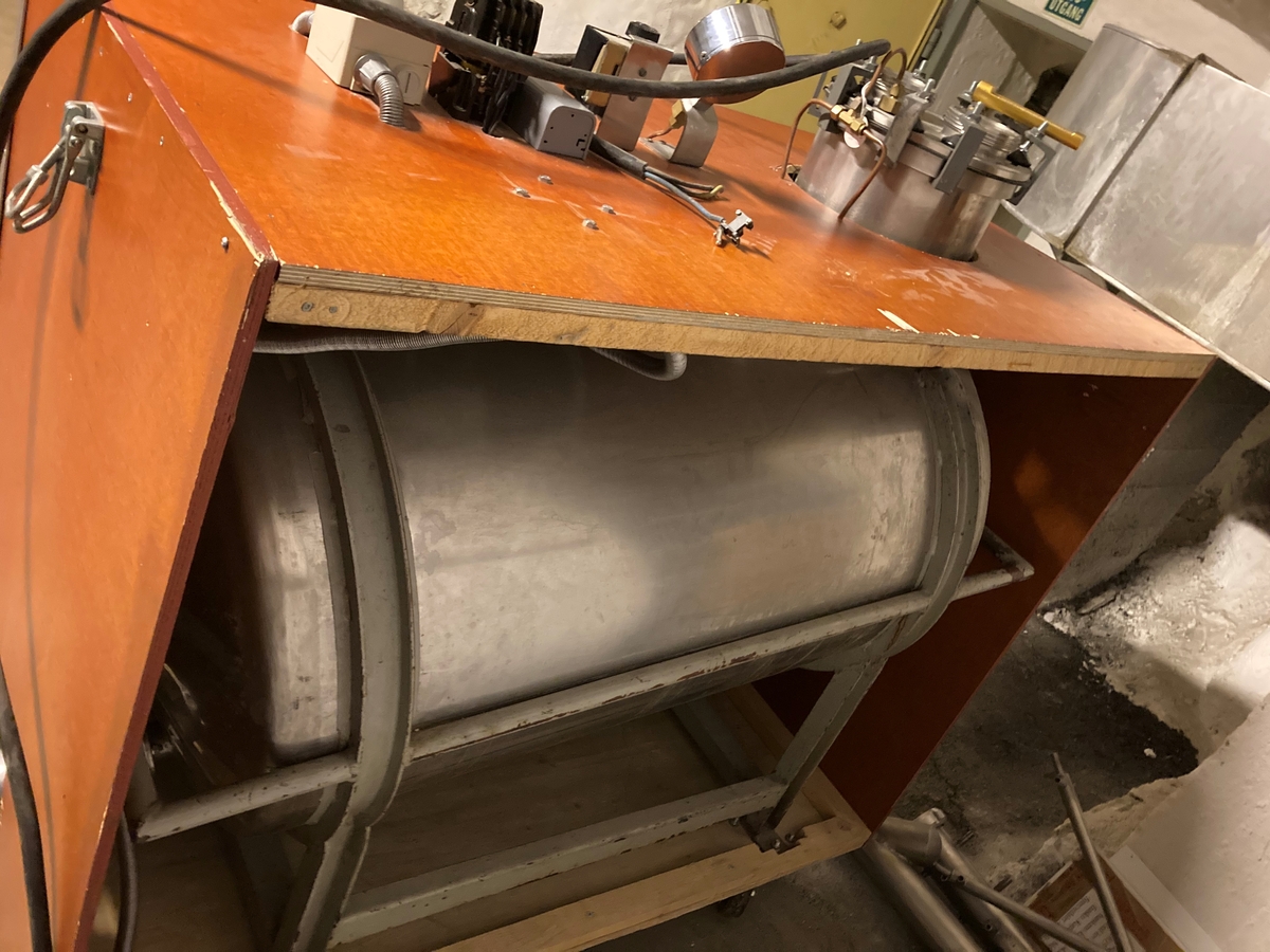 Stort hjemmebrentsapparat. Tanken er innebygd i en kasse av kryssfinér og hengslett lokk. På instrumentene som hører med står det: Bergs Maskin, Trondheim kp/cm2, Ranco, Trade mark registered, Penn. En stor sikring og en bryter 0-1-2.