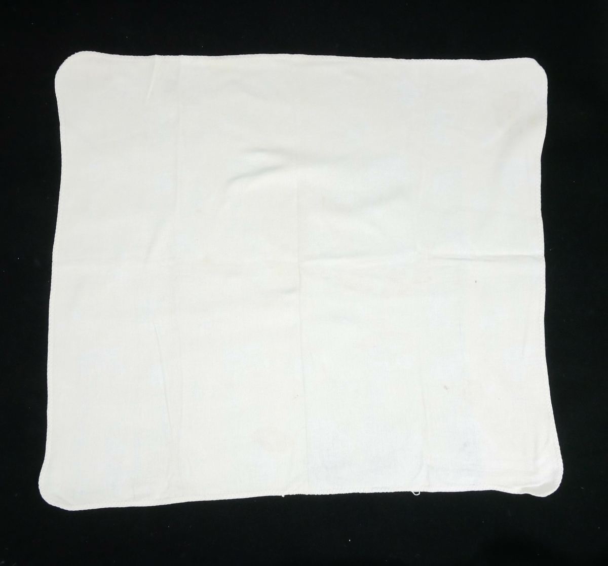 Lysegult pledd med gjentakende mønster i hvitt på den ene siden, på den andre mønster i gult på hvit bakgrunn. Runde hjørner. 