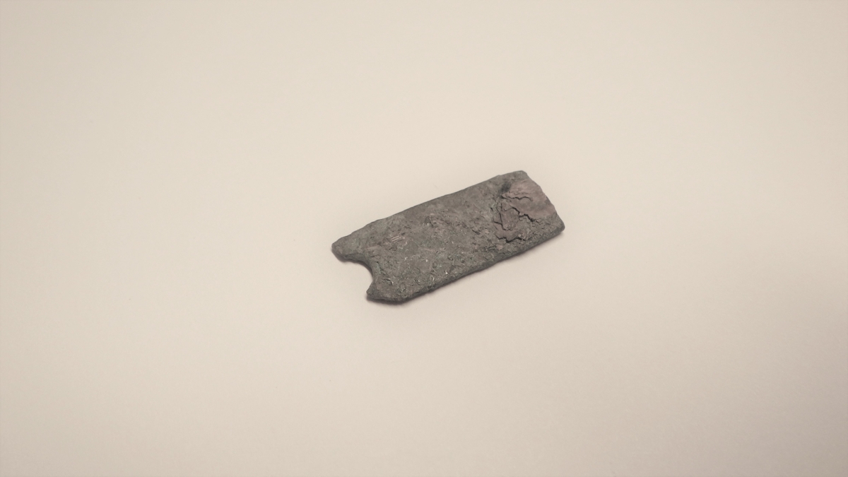 MALV: L. 26  B. 12 MM, REKTANGULÆRT, BÅNDFORMET UTEN DEKOR OG MED RESTER AVET HULL. 