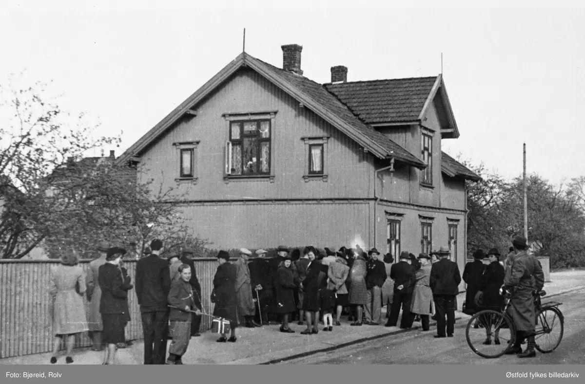 Da freden "brøt løs" i maidagene 1945. Menneskemengde utenfor Færders gate 29 på Fritznerbakken i Sarpsborg (huset ligger der fremdeles, 2025). Beboerne hadde funnet frem en radio som hadde vært gjemt vekk under krigen, og den ble plassert i vinduet slik at  folk på utsiden kunne høre sendingene om frigjøringen.