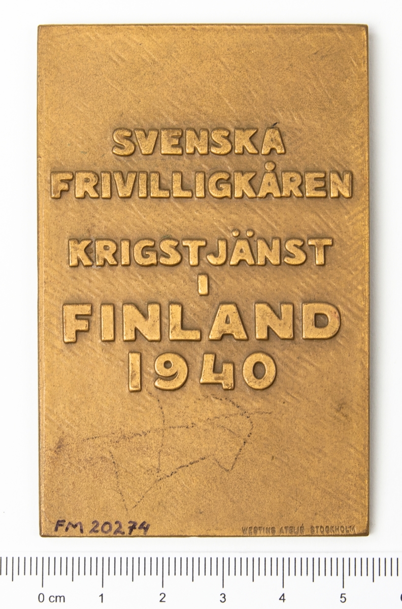 Minnesplakett Svenska Frivilligkåren i Finland. På åtsidan ett präglat motiv av ett lejon och texten "För Nordens Frihet och Sveriges Ära". På frånsidan texten "Svenska Frivilligkåren Krigstjänst i Finland 1940".