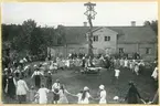 Västerås, Vallby friluftsmuseum.
Dans runt midsommarstången framför Tenngjutargården, Vallby friluftsmuseum. 1924.