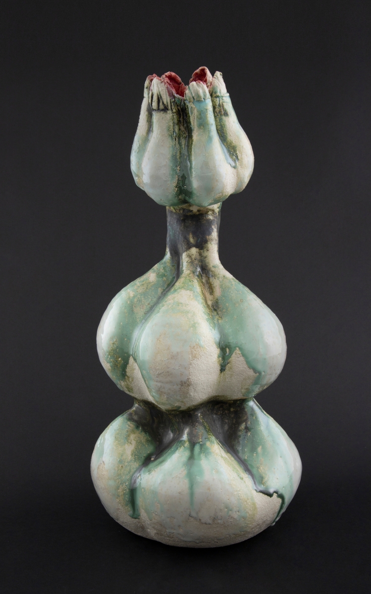 Håndmodellert skulptur i glasert steingods med oppreist holdning. Den har en organisk og asymmetrisk kalebassform som ender i en tulipanform med halvåpne kronblader. Keramikkskulpturen inngår i en installasjon bestående av 26 deler i ulike størrelser og med individuell utforming. De asymmetriske variasjonene gir et inntrykk av bevegelse, og den lett sykelige fargepaletten gir et uhyggelig og grotesk preg. Samtlige deler minner om kjøttetende planter.