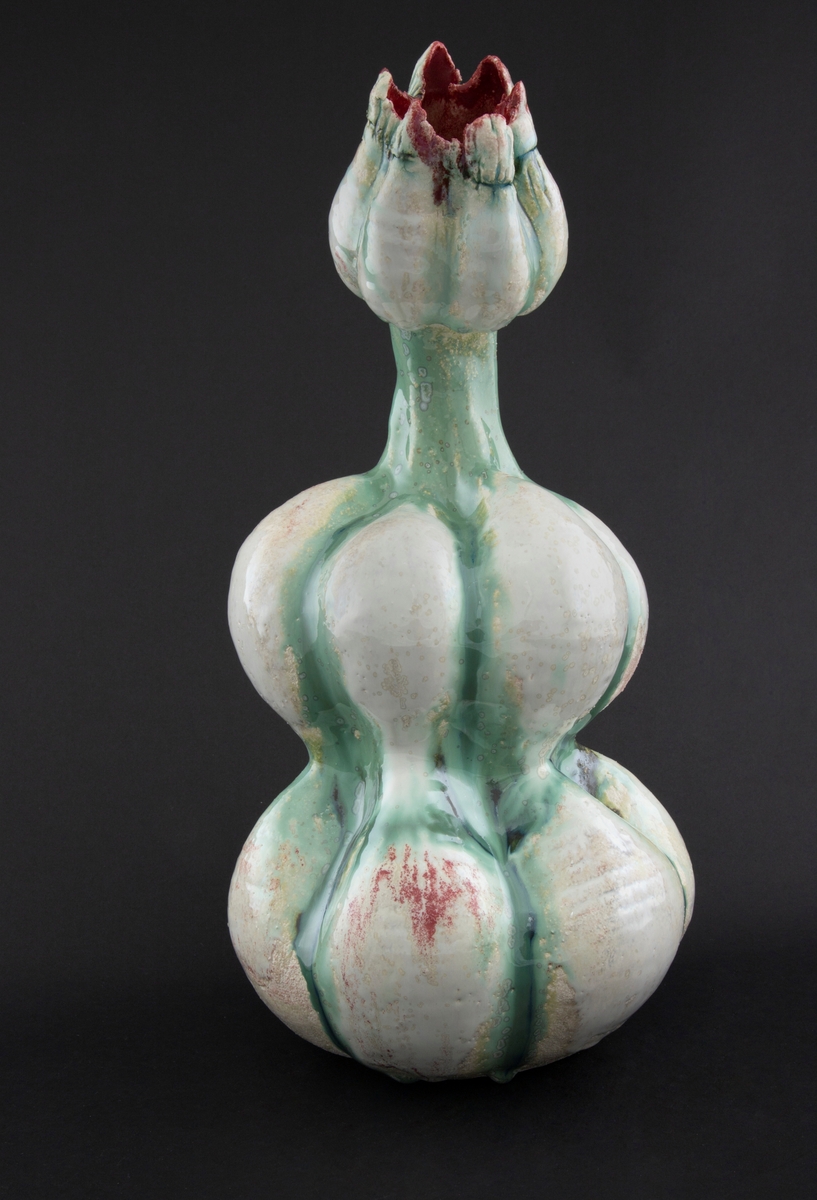 Håndmodellert skulptur i glasert steingods med delvis tiltende hode. Den har en organisk og asymmetrisk kalebassform som ender i en tulipanform med halvåpne kronblader. Keramikkskulpturen inngår i en installasjon bestående av 26 deler i ulike størrelser og med individuell utforming. De asymmetriske variasjonene gir et inntrykk av bevegelse, og den lett sykelige fargepaletten gir et uhyggelig og grotesk preg. Samtlige deler minner om kjøttetende planter.