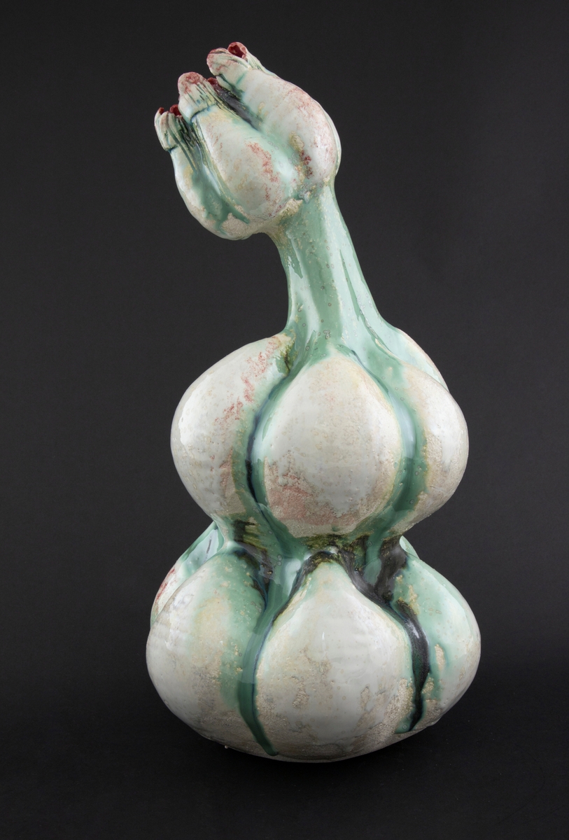 Håndmodellert skulptur i glasert steingods med delvis tiltende hode. Den har en organisk og asymmetrisk kalebassform som ender i en tulipanform med halvåpne kronblader. Keramikkskulpturen inngår i en installasjon bestående av 26 deler i ulike størrelser og med individuell utforming. De asymmetriske variasjonene gir et inntrykk av bevegelse, og den lett sykelige fargepaletten gir et uhyggelig og grotesk preg. Samtlige deler minner om kjøttetende planter.