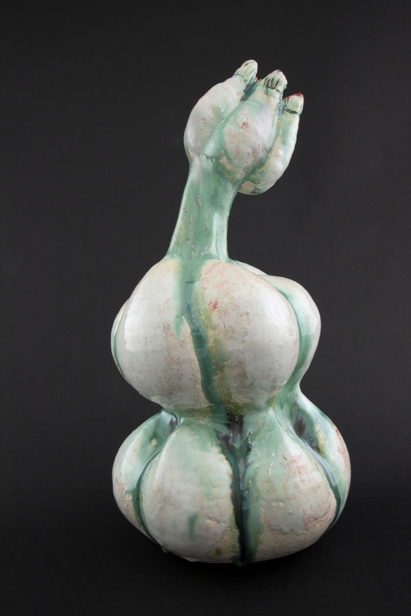 Håndmodellert skulptur i glasert steingods med delvis tiltende hode. Den har en organisk og asymmetrisk kalebassform som ender i en tulipanform med halvåpne kronblader. Keramikkskulpturen inngår i en installasjon bestående av 26 deler i ulike størrelser og med individuell utforming. De asymmetriske variasjonene gir et inntrykk av bevegelse, og den lett sykelige fargepaletten gir et uhyggelig og grotesk preg. Samtlige deler minner om kjøttetende planter.