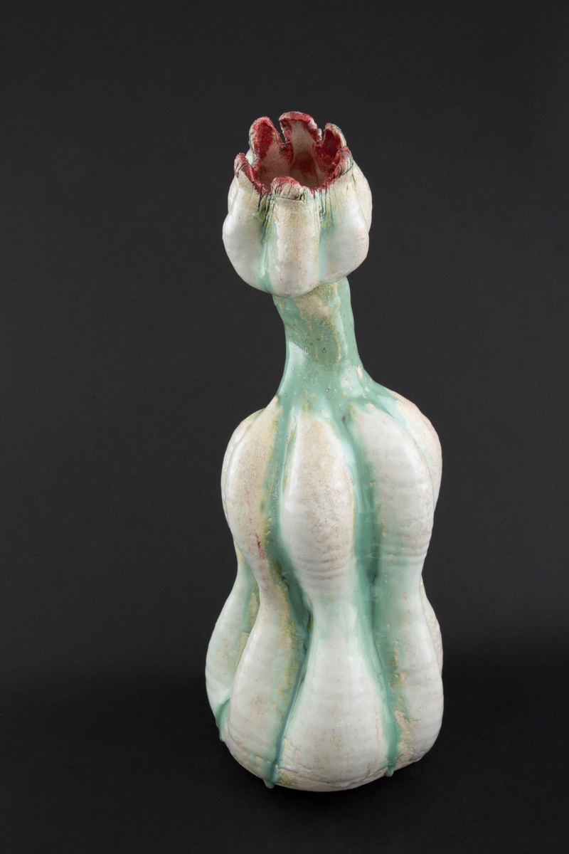Håndmodellert skulptur i glasert steingods med oppreist holdning. Den har en organisk og asymmetrisk kalebassform som ender i en tulipanform med halvåpne kronblader. Keramikkskulpturen inngår i en installasjon bestående av 26 deler i ulike størrelser og med individuell utforming. De asymmetriske variasjonene gir et inntrykk av bevegelse, og den lett sykelige fargepaletten gir et uhyggelig og grotesk preg. Samtlige deler minner om kjøttetende planter.